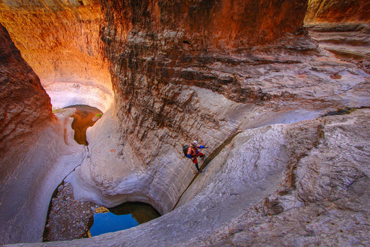 Person exploring a narrow canyon with water below